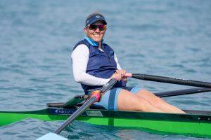 Smiling man in a single scull rowing at Lake Ruataniwha New Zealand in the master rowing championships 2023